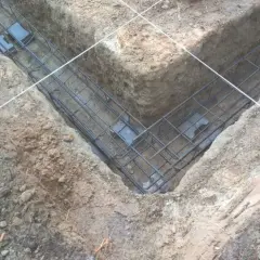 Gotowe zbrojenie fundamentu w wykopie. Stalowe pręty tworzą siatkę, która wzmocni beton.