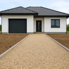 Nowy podjazd z kruszywa przed białym domem z garażem.