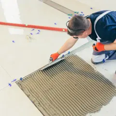 Fachowiec nakłada klej pod płytki 60x30. Precyzyjne układanie to klucz do estetyki i trwałości podłogi.