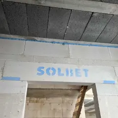 Szczelina dylatacyjna z pianki montażowej między blokami betonowymi, z logo "SOLBET".