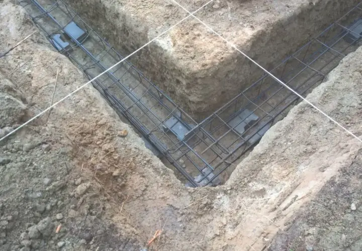 Gotowe zbrojenie fundamentu w wykopie. Stalowe pręty tworzą siatkę, która wzmocni beton.