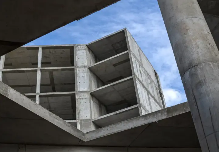 Surowy beton budowy, z widocznymi piętrami i słupami, pod błękitnym niebem. Pianobeton wkrótce nada mu formę.