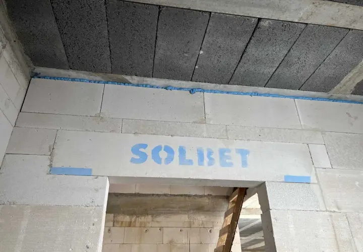 Szczelina dylatacyjna z pianki montażowej między blokami betonowymi, z logo "SOLBET".