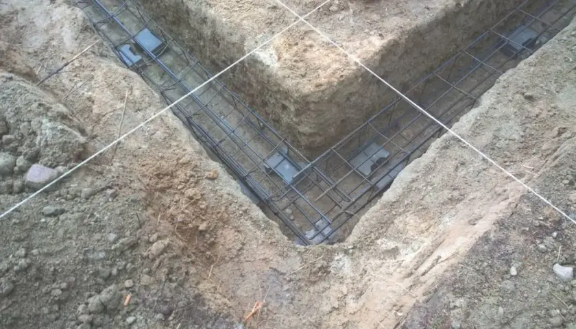 Gotowe zbrojenie fundamentu w wykopie. Stalowe pręty tworzą siatkę, która wzmocni beton.