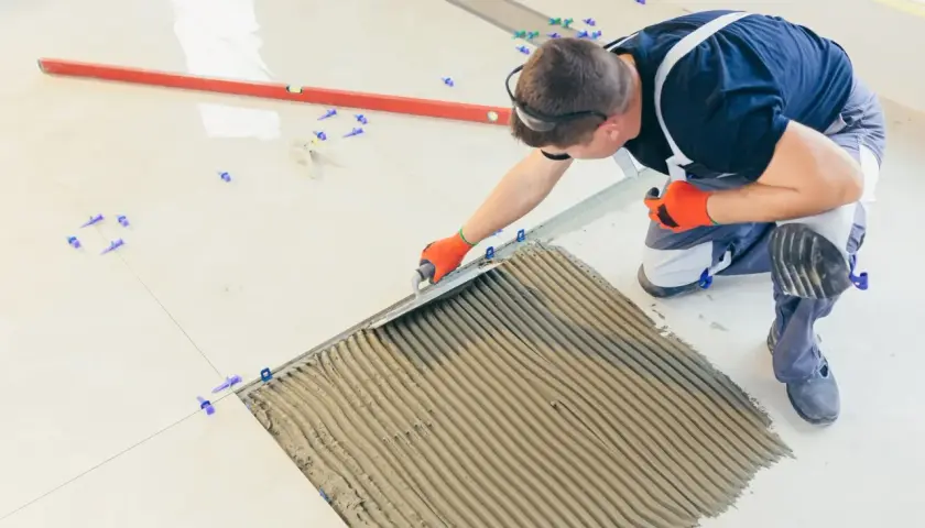 Fachowiec nakłada klej pod płytki 60x30. Precyzyjne układanie to klucz do estetyki i trwałości podłogi.