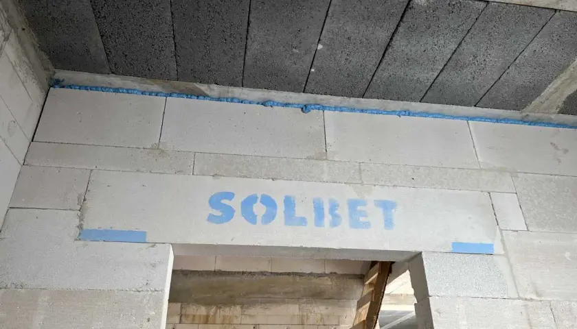 Szczelina dylatacyjna z pianki montażowej między blokami betonowymi, z logo "SOLBET".