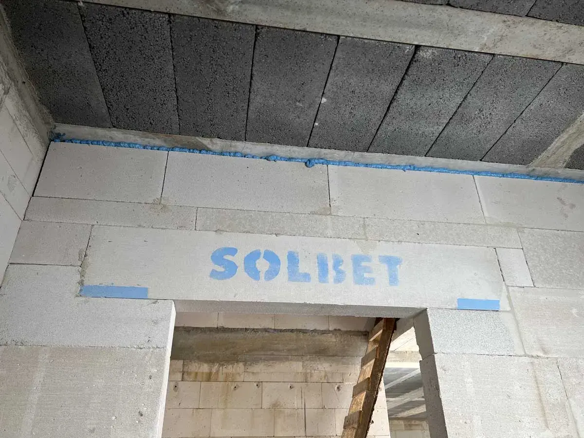 Szczelina dylatacyjna z pianki montażowej między blokami betonowymi, z logo "SOLBET".