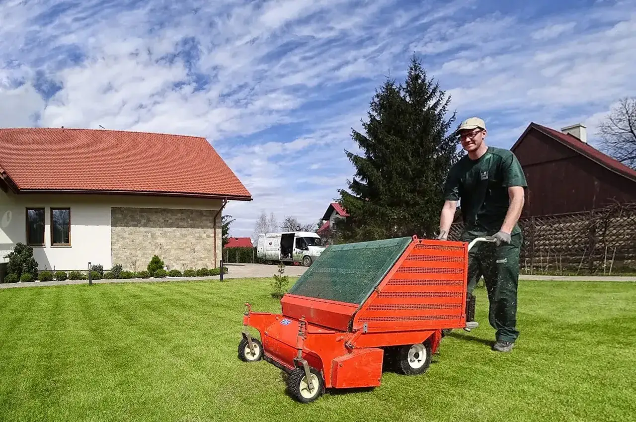 Ogrodnik z maszyną do aeracji przygotowuje trawnik do tego, jak siać trawę na starym trawniku.
